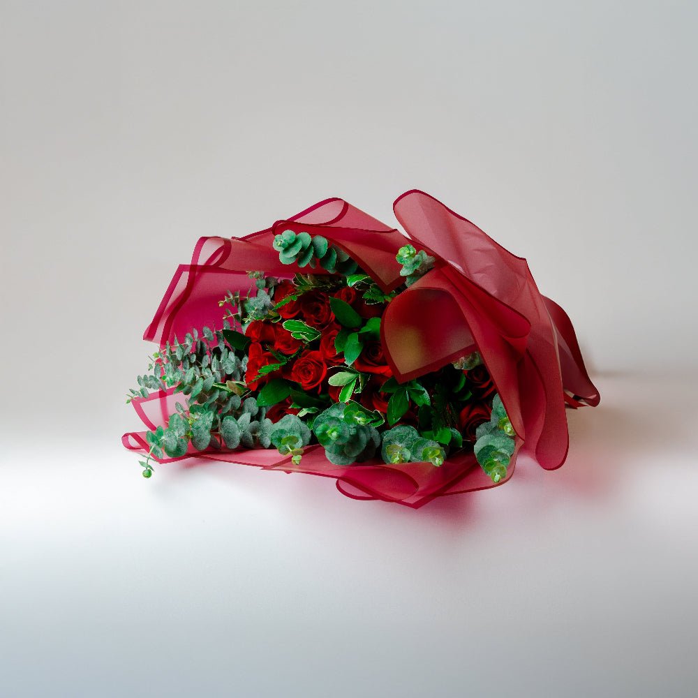 AMOROSSA - Bouquet 24 Ahava Premium - Ramo de rosas rojas con follaje verde envuelto en tul rojo para regalar flores y mandar rosas con delivery rápido de flores.